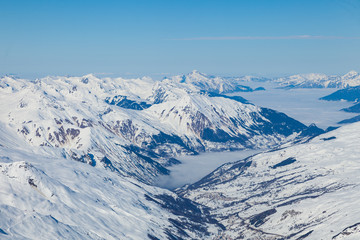Naklejka premium Aerial view to mountain valley with clouds at French alps. Mountain ski resort Three Valleys, France.