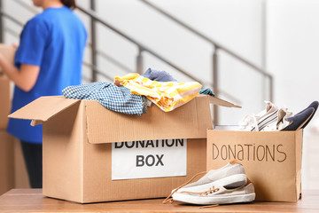 Donation boxes with clothes and shoes on table indoors