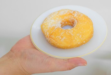 Hand Holding Delicious Glazed Donut with Sugar