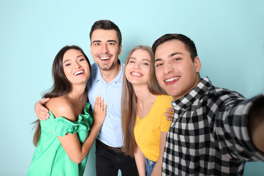Young happy friends taking selfie against color background