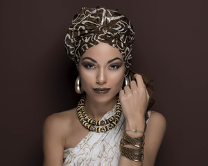 beauty girl with turban and brown makeup in front of a brown background with earrings