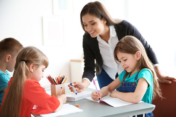 Female teacher helping girl with her task in classroom at school