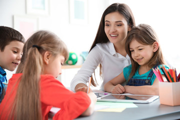 Fototapeta na wymiar Female teacher helping girl with her task in classroom at school