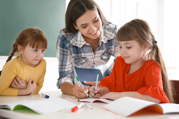 Female teacher helping girl with her task in classroom at school