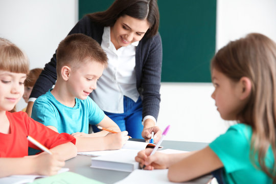 Female teacher helping boy with his task in classroom at school