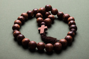Wooden  rosary and cross on green background.