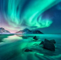 Fotobehang Koraalgroen Aurora. Noorderlicht op de Lofoten-eilanden, Noorwegen. Hemel met poollichten, sterren. Nacht winterlandschap met aurora, zee met lucht reflectie, stenen, zandstrand en bergen. Groene aurora borealis