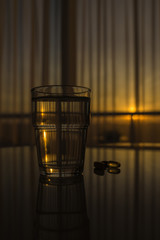 Glass of water an a pill of fish oil at table in sunrise