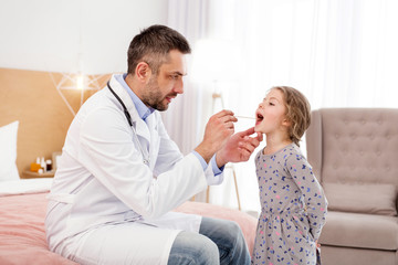 Great doctor. Serious professional doctor examining his patient and looking in her throat