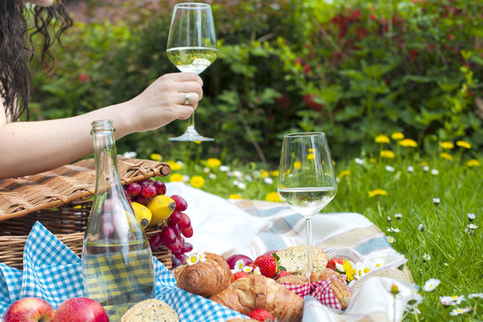 Wine and croissants on a picnic. A glass of wine in a woman's hand. Tasty food. Romantic weekend. Free space for text