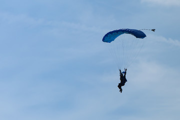 Parachutist with Blue Parachute against Clear Blue Sky