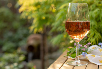 One cold rose wine glass served on outdoor terrace in garden with flowers