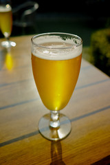 One cold light unfiltered beer in glass served on sunny outdoor terrace in garden