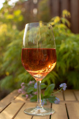 One cold rose wine glass served on outdoor terrace in garden with flowers