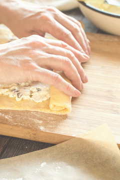 Woman is preparing a roll of dough with a curd filling