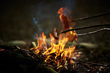 Kiełbasa pieczona nad ogniskiem w płomieniach ognia.  