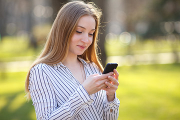 Young cute woman messaging using smart phone outdoors.Conversati