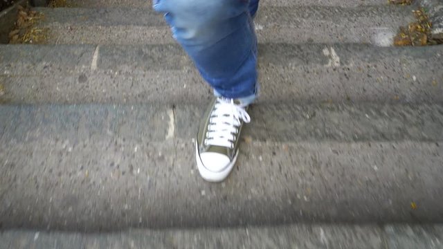 man with blue geans and sneaker shoes goes up the stairs
