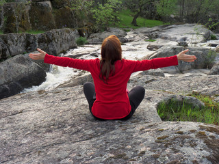 Mujer joven meditando frente al río