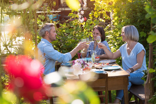 Summer, a group of friends in their forties gather at dinner in garden