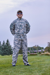 Portrait of full-length army officer in the park. Severe serious commander in camouflage.