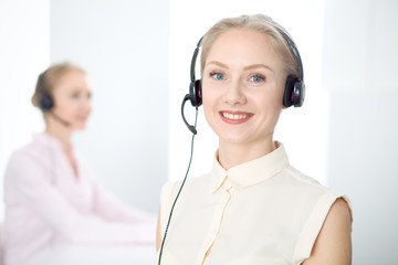 Image of bright call center. Focus on young beautiful woman in a headset