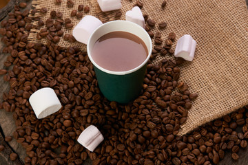 Green Take away coffee cup white marshmallow and roasted coffee beans on brown sackcloth background