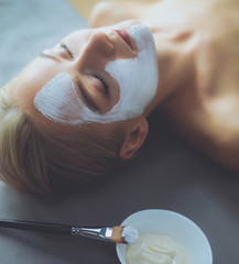 Fototapeta premium Face mask.Beautiful young girl at spa ,cosmetician woman applying facial mask