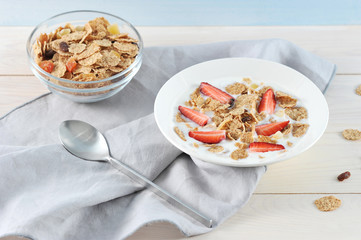 Corn flakes with yogurt in a plate. To the flakes were added dried fruits and fresh strawberries....