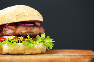 Fresh and delicious home made burger on wooden board with copy space. Closeup.