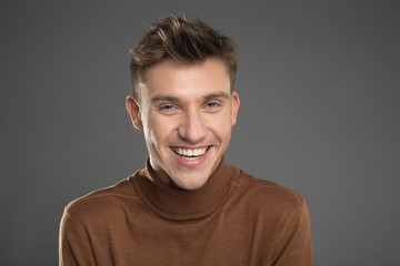 Portrait of cheerful man in pullover staring and laughing. Isolated on background