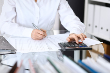 Female bookkeeper or financial inspector  making report, calculating or checking balance. Internal Revenue Service checking financial document. Audit concept in business