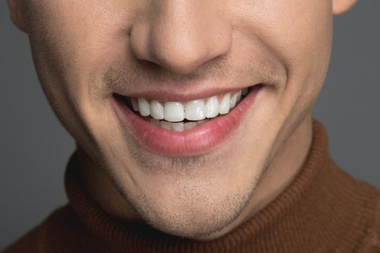 Health And Care Concept. Close Up Of Man Face Showing Groomed And White Teeth