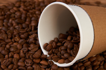 Take away coffee paper cups and roasted coffee beans on rustic wooden table background, close-up.