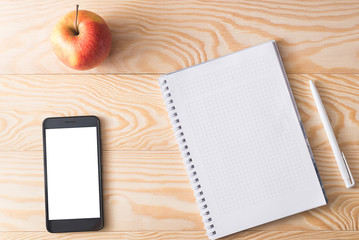 apple, phone and notebook on a wooden background