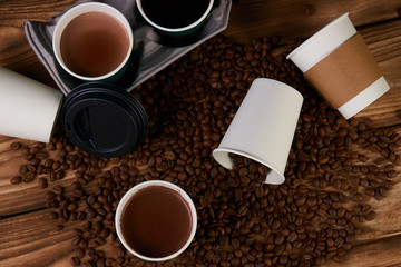 Composition with Takeaway coffee paper cups with hot chocolate drink and roasted coffee beans on wooden table background