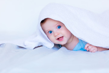 Fototapeta na wymiar Little child boy with blue eyes in white bed