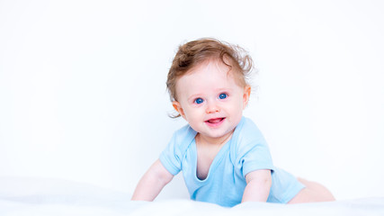 Little child boy with blue eyes in white bed