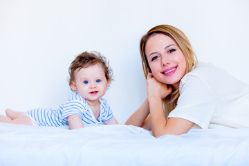 Young mother and little child boy lying down in white bed