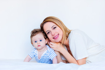 Young mother and little child boy lying down in white bed
