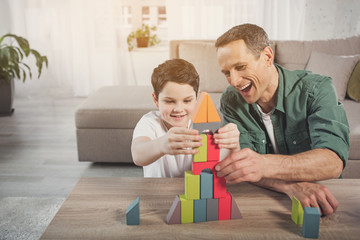 Obraz premium Happy family is playing together at home. They are making construction from small details and laughing