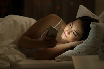 Girl using a smart phone on the bed in the night