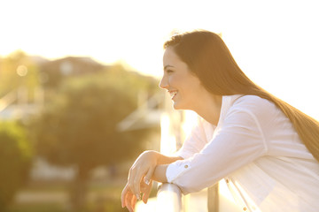 Profile of a happy woman looking away in a balcony