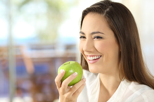 Happy woman holding an apple looking away