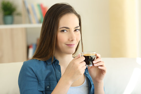 Relaxed woman holding a coffee cup looking at camera