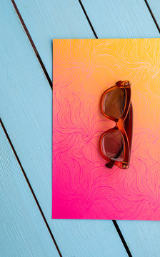 Top view close up of contemporary sunglasses locating on floral printed carton on blue surface. Fashion concept