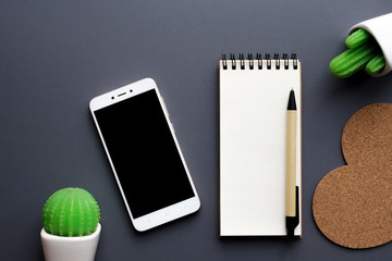office desk table with blank notepad, smartphone, stationery and cacti