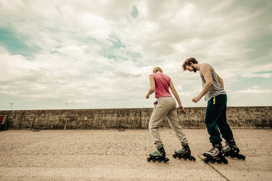 Two people race together riding rollerblades.