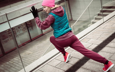 Sporty girl stretching outdoor on city street.