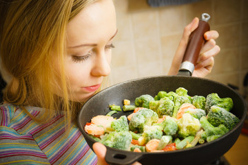 Woman cooking stir fry frozen vegetable on pan